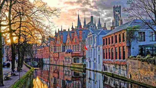 Una foto del principale canale di bruges, con i palazzi riflessi nell'acqua (Il Mondo Attraverso)