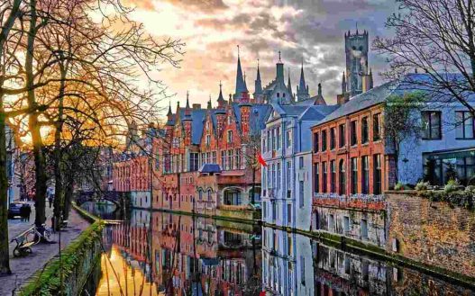 Una foto del principale canale di bruges, con i palazzi riflessi nell'acqua (Il Mondo Attraverso)